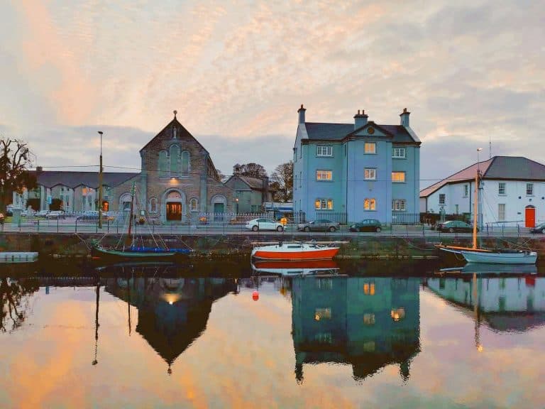 Buildings in Galway bay reflected on the water below during sunset.