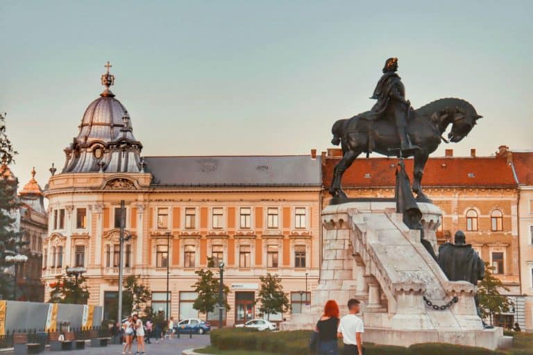 Union Square in Cluj-Napoca, Romania with a large silver domed building and a statue of a man on a horse.